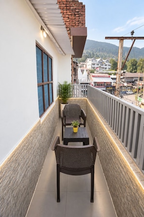Un balcón con vistas a un paisaje urbano, una mesa con sillas y una planta en maceta.