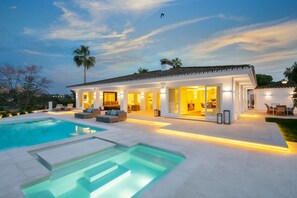 Ein modernes Haus mit Swimmingpool, großen Fenstern und Außenbereich mit Sitzgelegenheiten.