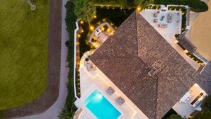 An aerial view of a property with a swimming pool, outdoor seating, and a well-maintained garden. - Vrbo Property (Marbella)