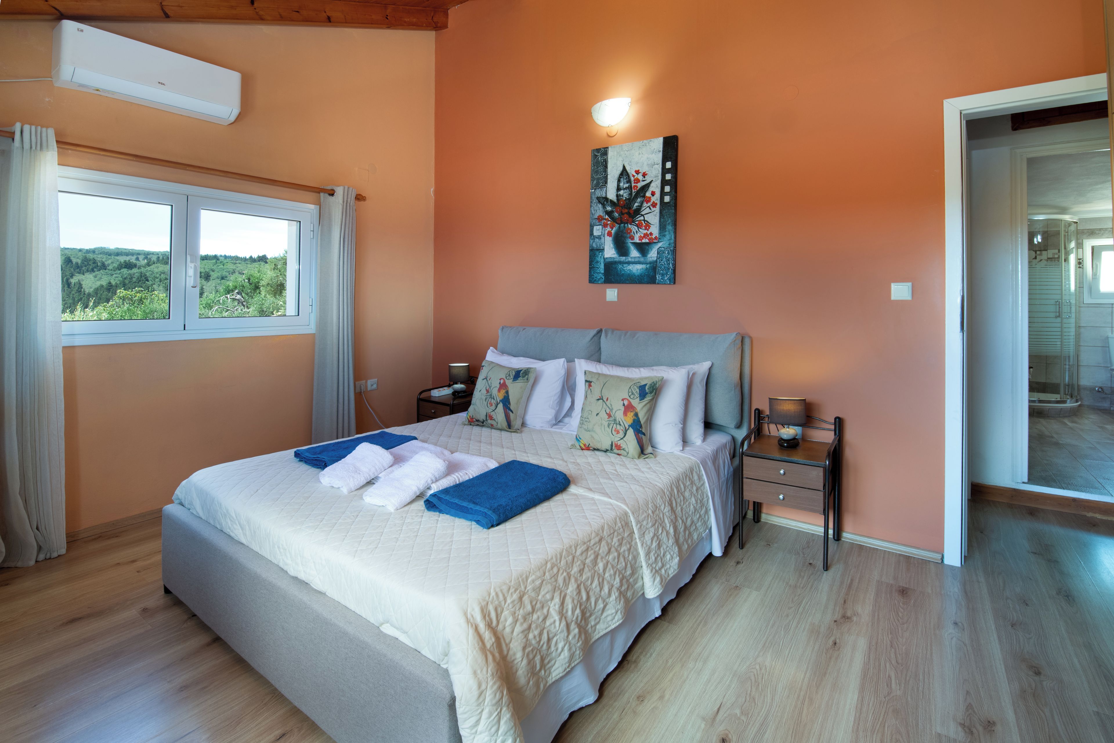 A bedroom with a large bed, a nightstand, a lamp, and a painting on the wall.