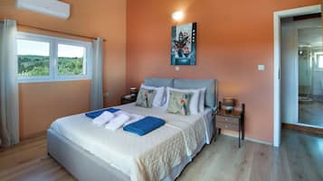 A bedroom with a large bed, a nightstand, a lamp, and a painting on the wall.