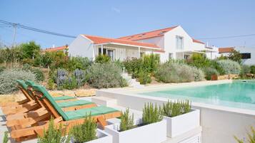 A modern house with a swimming pool, outdoor seating, and a garden.