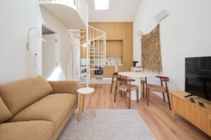 A modern living room with a spiral staircase, a dining area with a round table, and a kitchen in the background. - NEW! A Quiet Retreat by the Atlantic Coast (Encarnação)