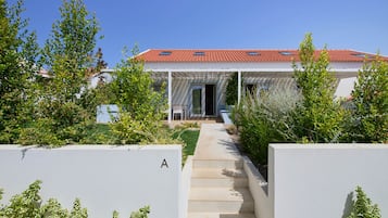 A modern house with a red-tiled roof, a covered porch, and a pathway leading to the entrance.