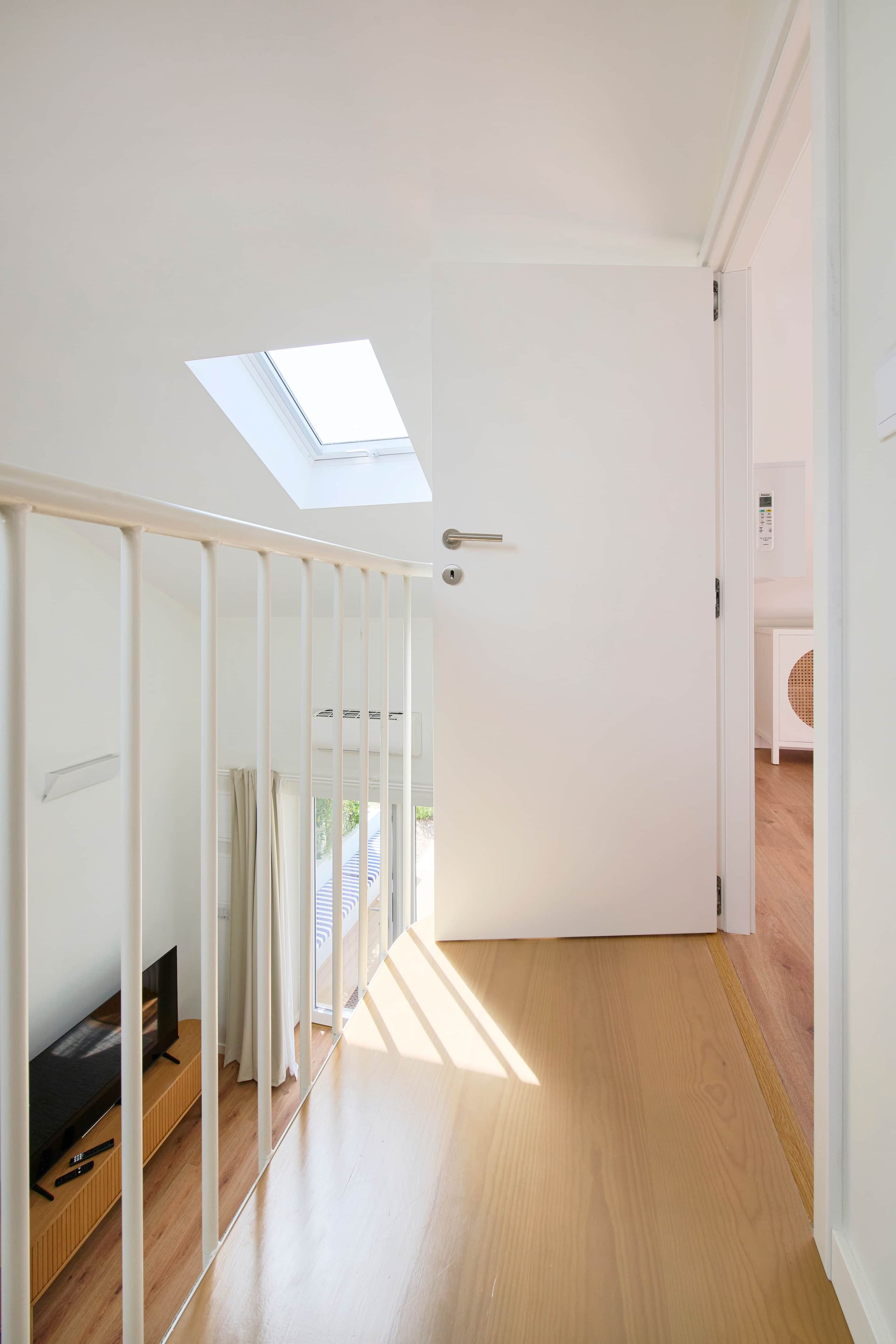 A hallway with a skylight, wooden flooring, a white door, and a view of an outdoor area.