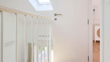 A hallway with a skylight, wooden flooring, a white door, and a view of an outdoor area.