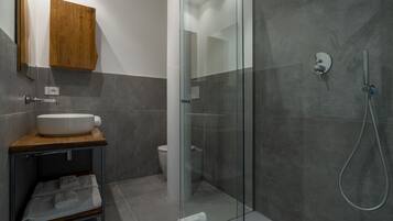 Un bagno moderno con cabina doccia in vetro, un mobile vanitario in legno e un lavandino bianco.