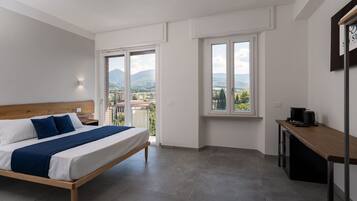 Ein Schlafzimmer mit Bett, Schreibtisch und Blick auf Stadt und Berge.