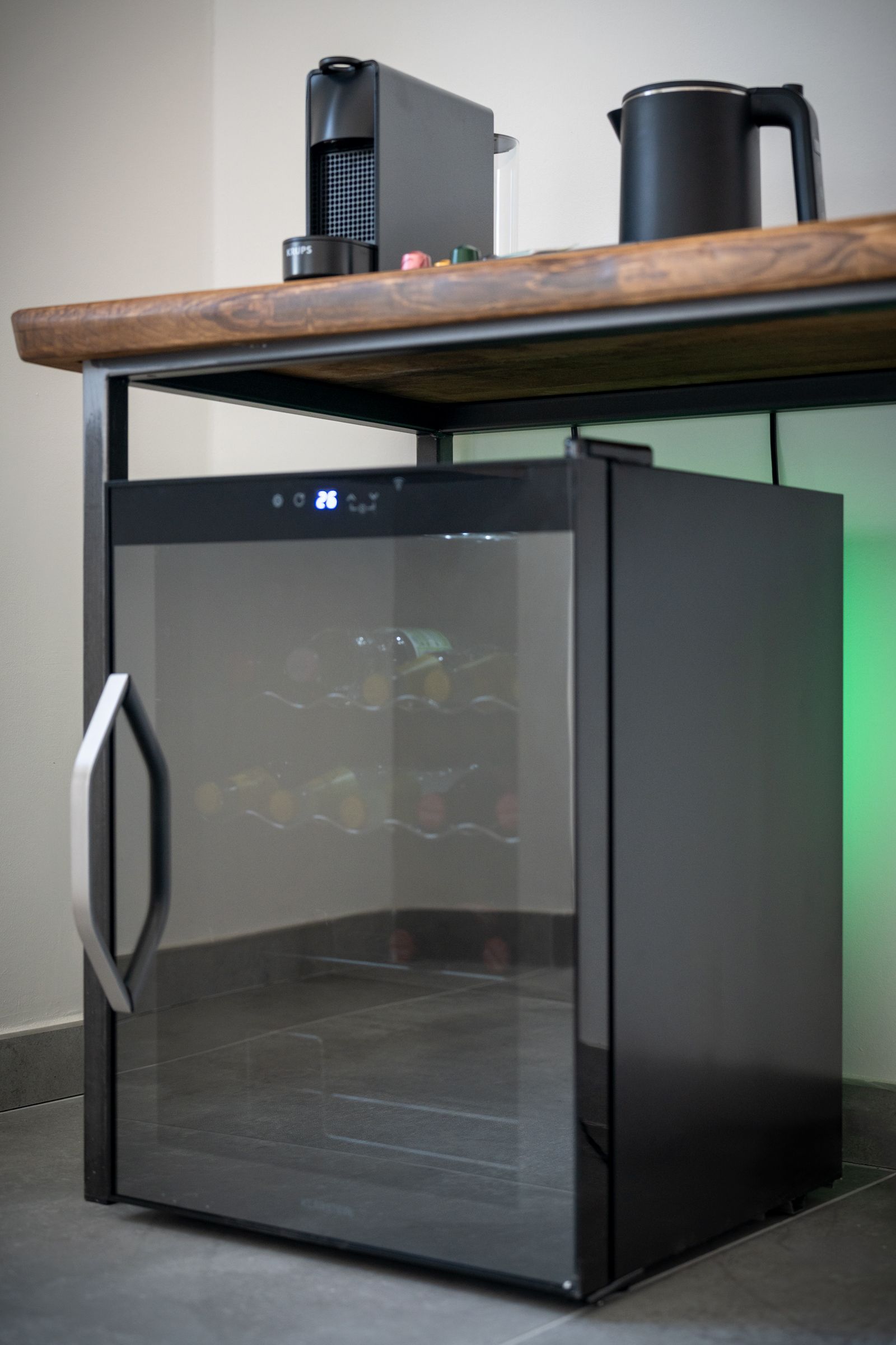 Ein kompakter Kühlschrank mit digitalem Display, einer Glastür und einer darüberliegenden Holzauszug.