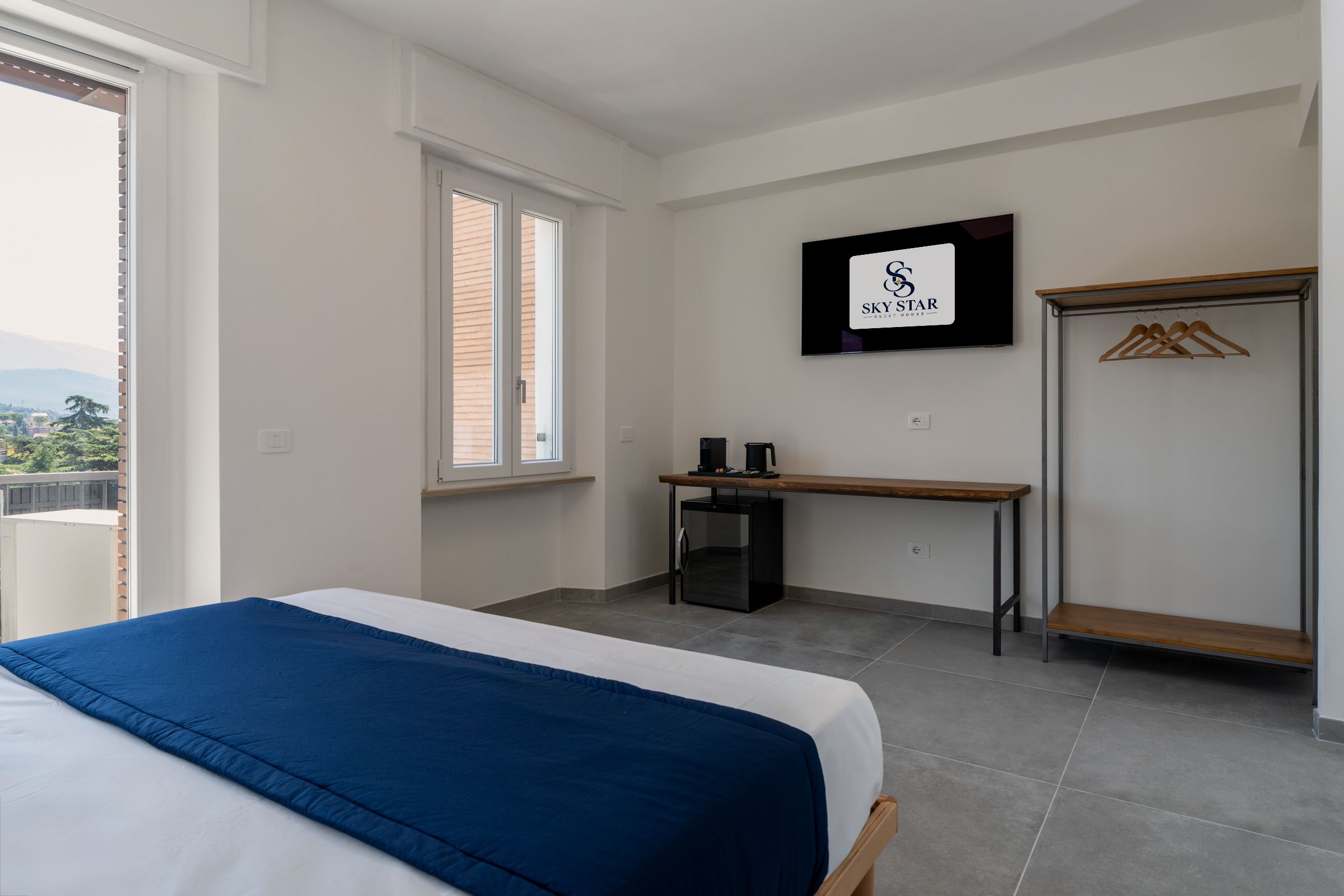 Une chambre d’hôtel équipée d’un lit, d’un bureau, d’une armoire et d’un téléviseur affichant le logo SKY STAR.