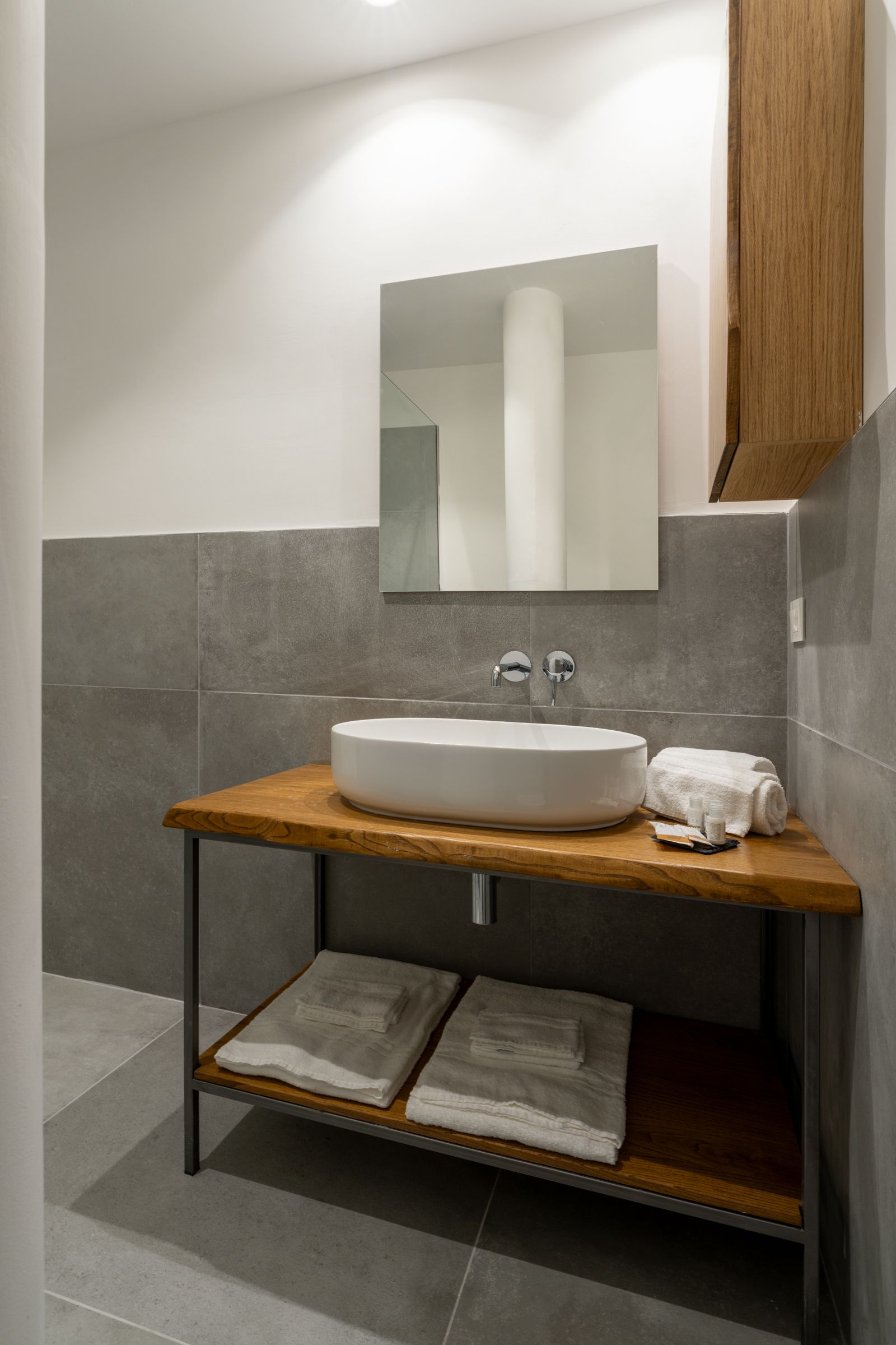 Ein modernes Badezimmer mit einem Holzlagerflächezerspiegel und einem weißen Waschbecken.