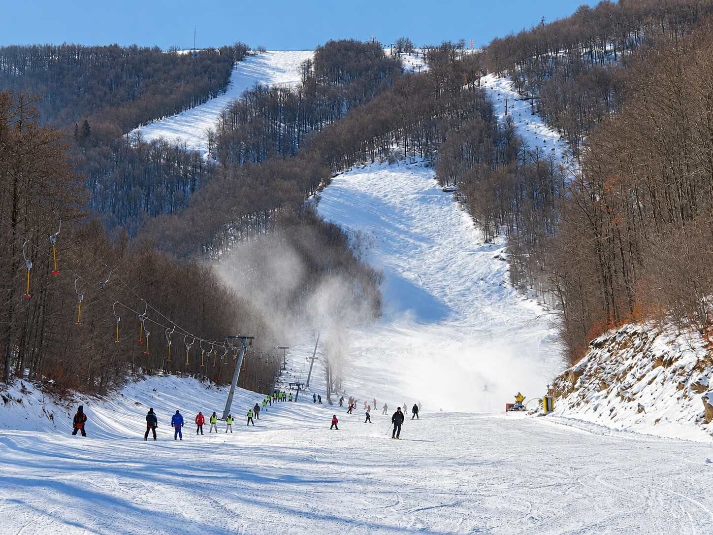 A ski slope with skiers and a ski lift.