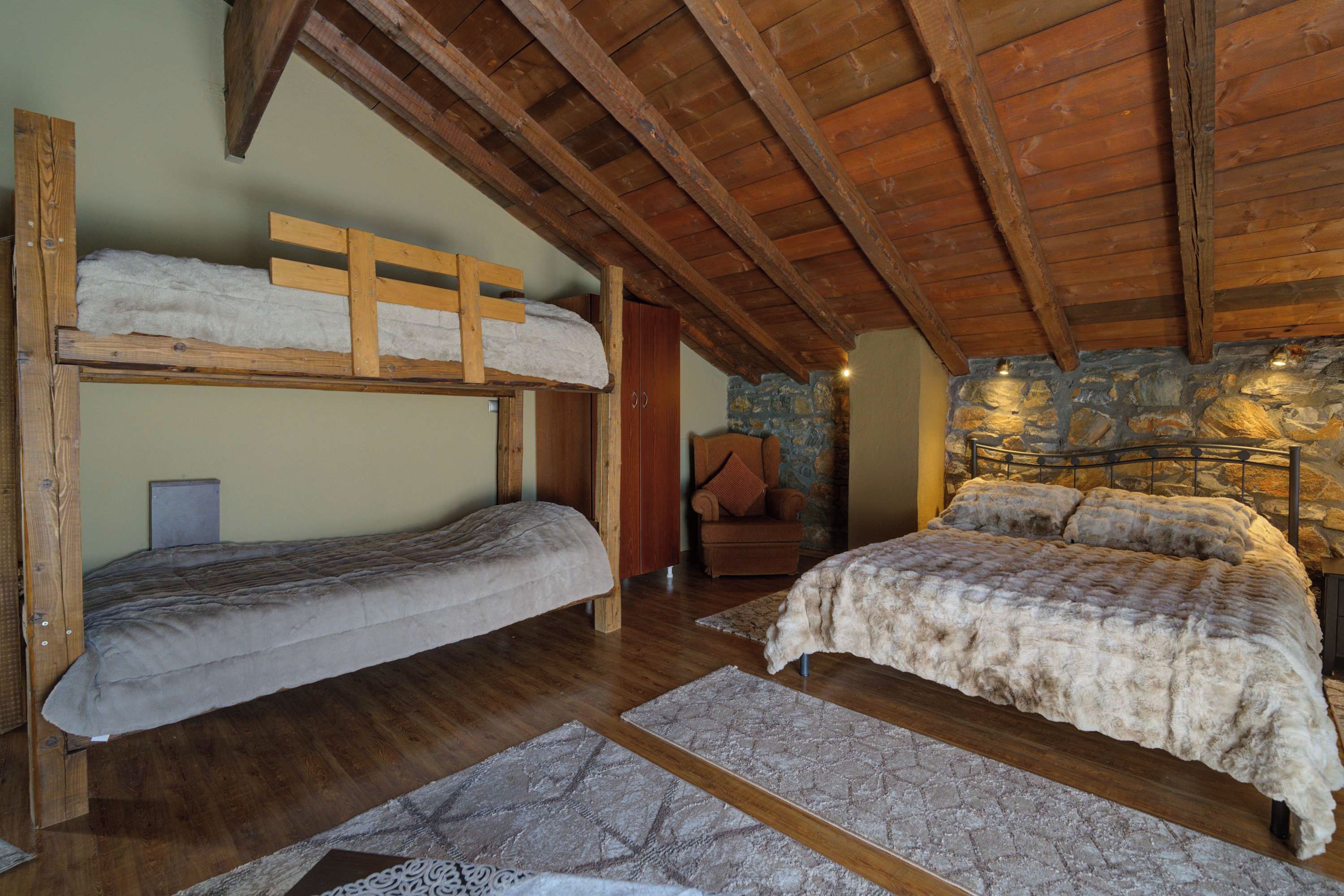 Een rustieke kamer met houten stapelbedden, een stenen muur en een gezellige open haard.