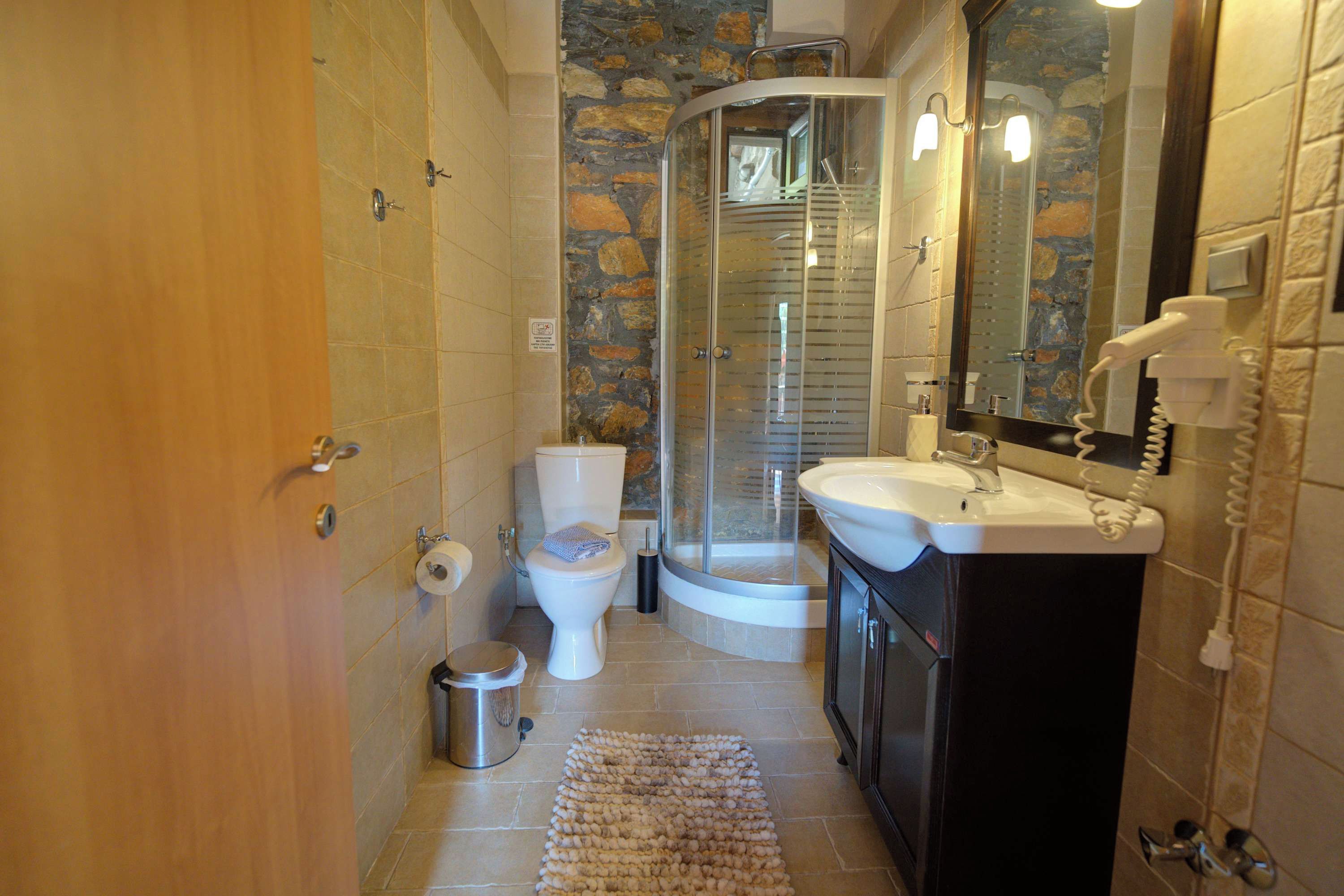 Ein Badezimmer mit Toilette, Waschbecken, Dusche und einer gläsernen Duschkabine.