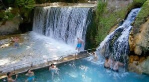 A natural hot spring with a waterfall, surrounded by greenery. - Remos Villas - Luxury Suites in Northern Greece (Agios Pavlos)
