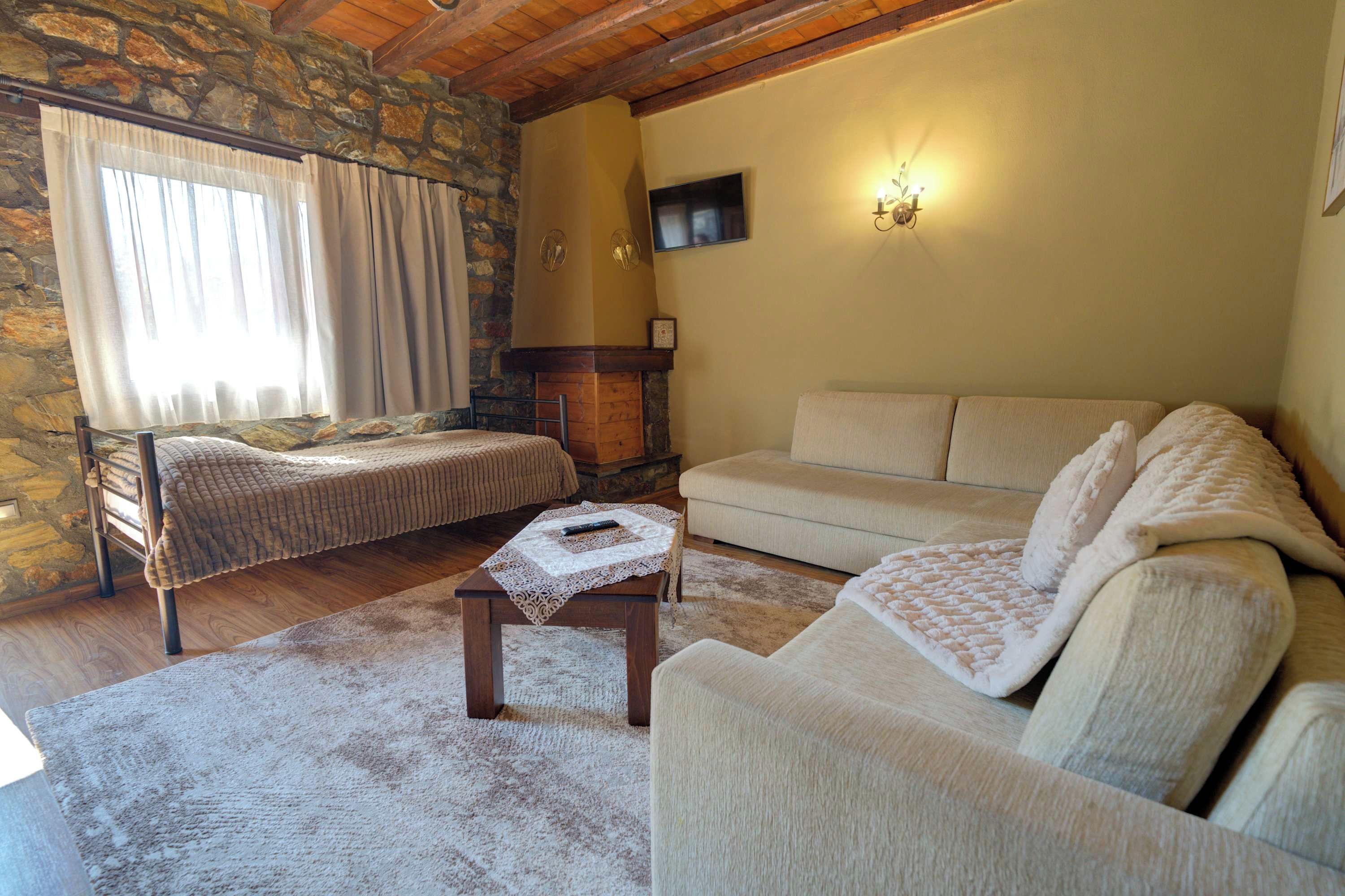 Ein gemütliches Wohnzimmer mit Steinwand, Kamin, einer Couch, einem Bett und einem Fernseher.