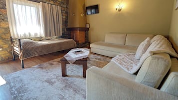 Ein gemütliches Wohnzimmer mit Steinwand, Kamin, einer Couch, einem Bett und einem Fernseher.