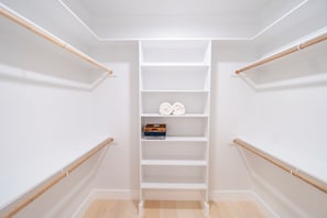 A walk-in closet with white shelving, a wooden floor, and a metal rack on the left. - Quiet 3-bedroom house in charming West Tawakoni beside the lake (Quinlan)