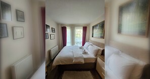 Ein Hotelzimmer mit Doppelbett, Heizkörper, einem fenster mit Vorhängen und einem Gemälde an der Wand.