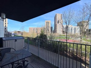 Ein Balkon mit Blick auf hohe Gebäude und einen umzäunten Garten.