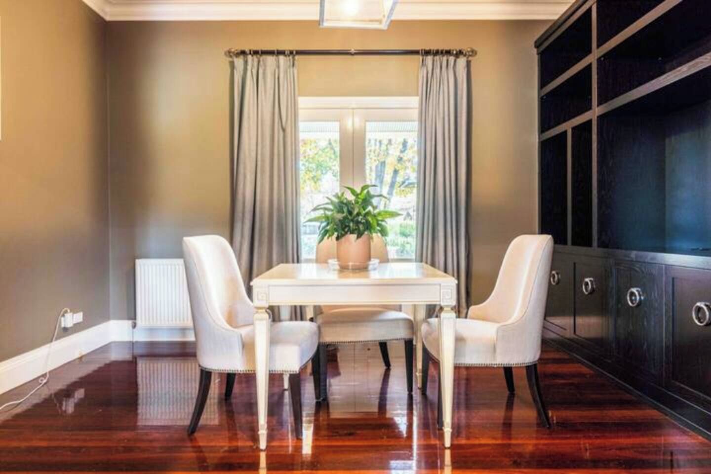 A dining area with a table and chairs, a potted plant, and a large cabinet.