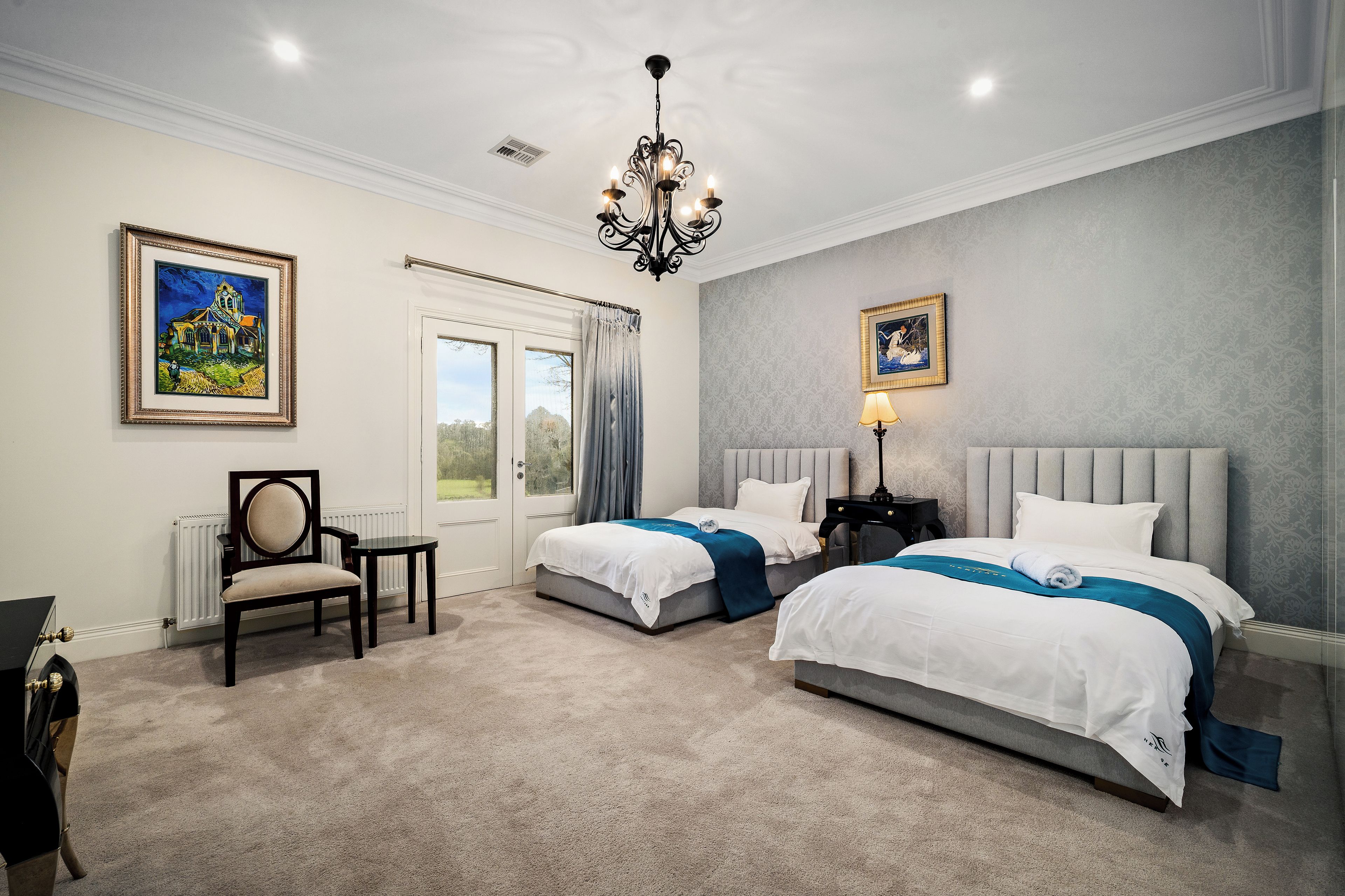 A hotel room with two beds, a chandelier, and artwork on the walls.
