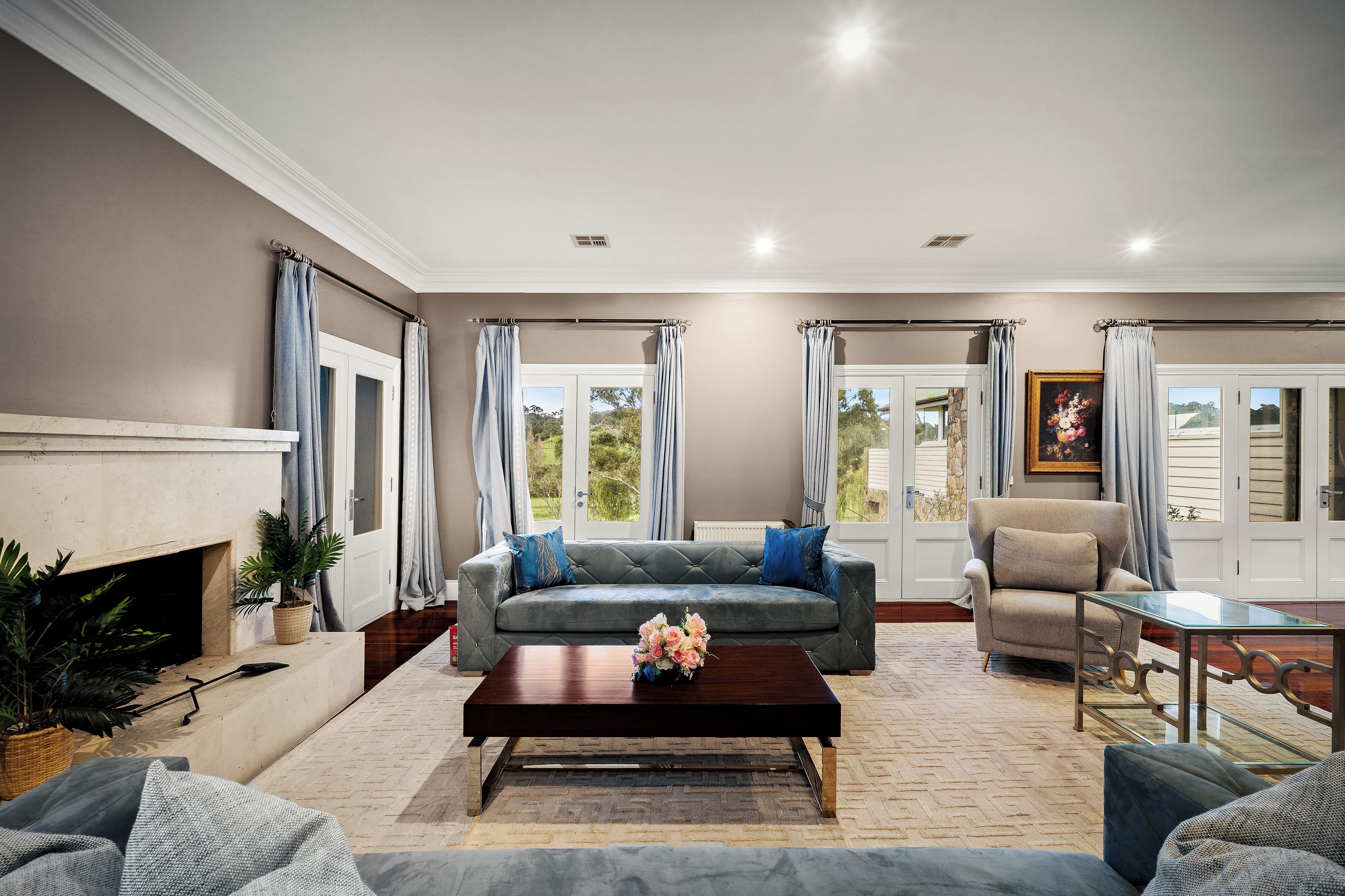 A living room with a grey sofa, a coffee table, a fireplace, and a view through the windows.