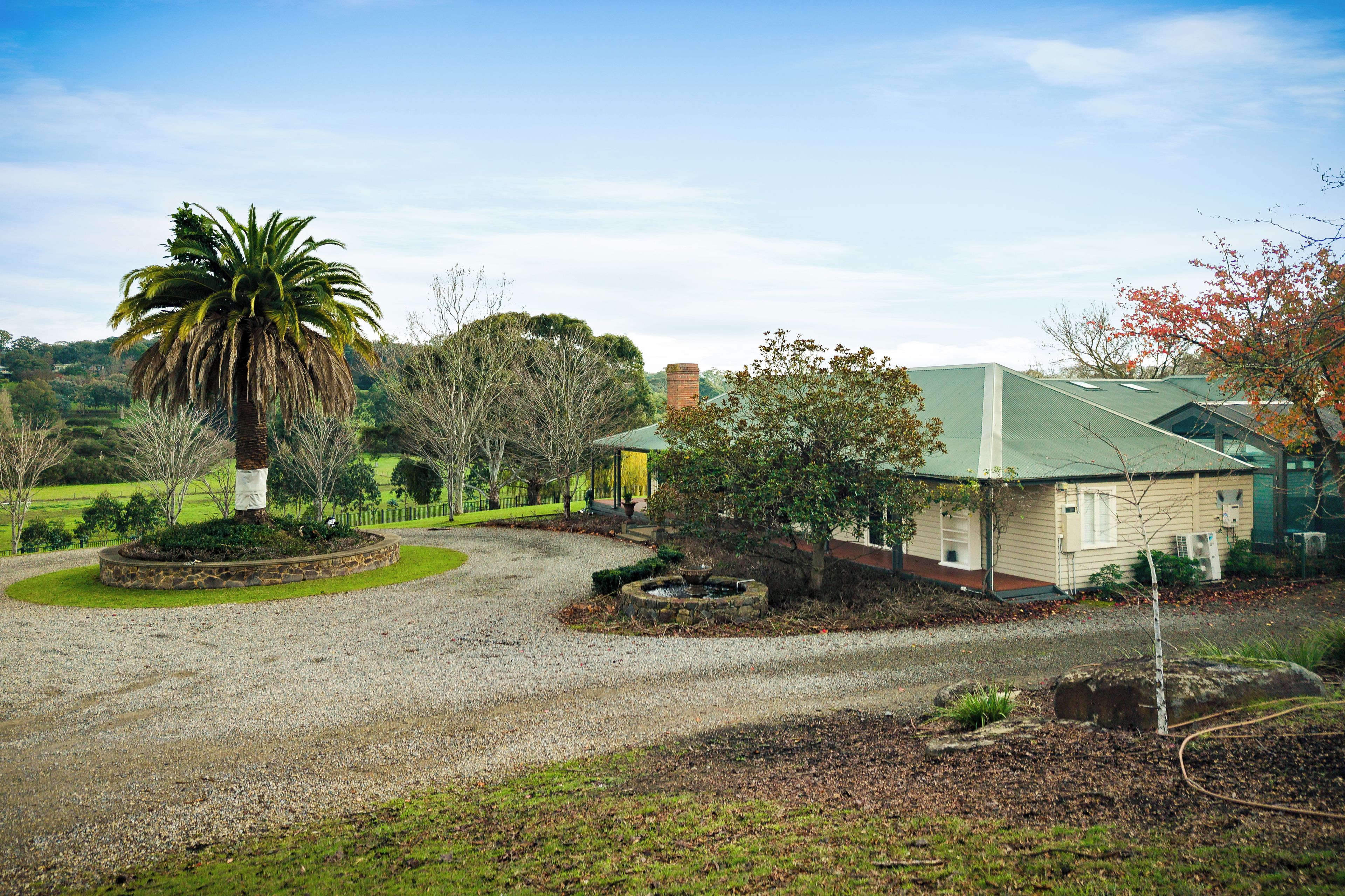 A building with a green roof, surrounded by a gravel driveway and landscaped areas.