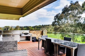 An outdoor patio with a grill, wicker furniture, and a view of a green landscape. - Grand Leisure Estate in Yarra Valley (Wonga Park)