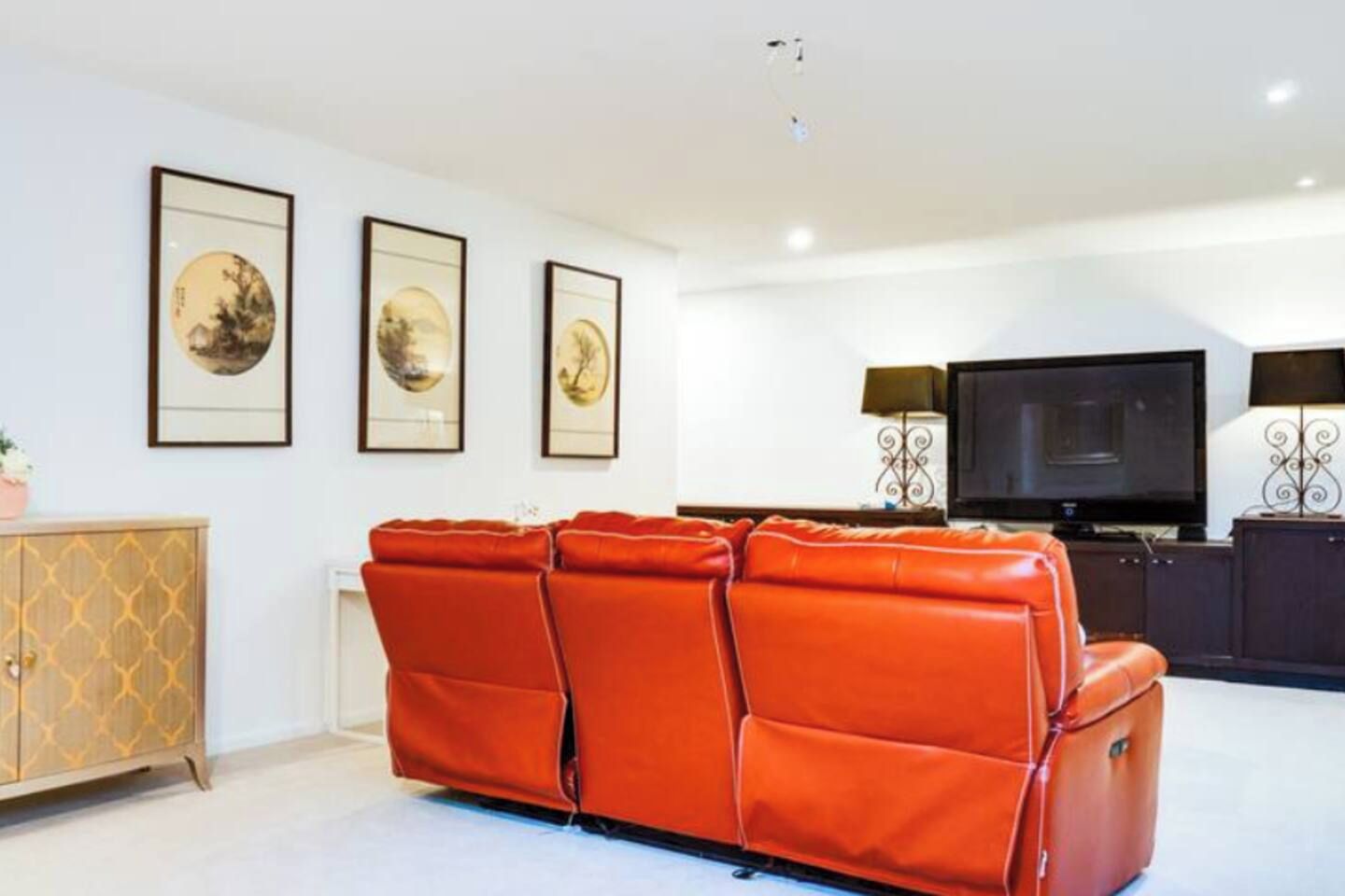 A living room with a sofa, a television, and framed artwork on the wall.