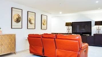 A living room with a sofa, a television, and framed artwork on the wall.