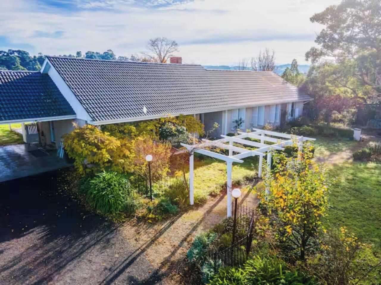 A residential property with a covered porch, a fenced garden, and a view of the surrounding landscape.
