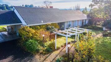 A residential property with a covered porch, a fenced garden, and a view of the surrounding landscape.
