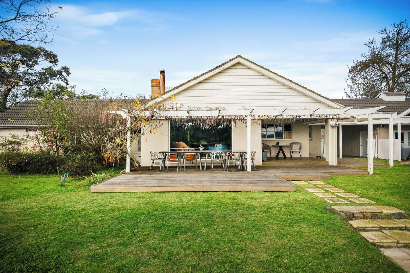 A residential property with a covered patio, a swimming pool, and a well-maintained lawn.