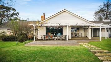 A residential property with a covered patio, a swimming pool, and a well-maintained lawn.