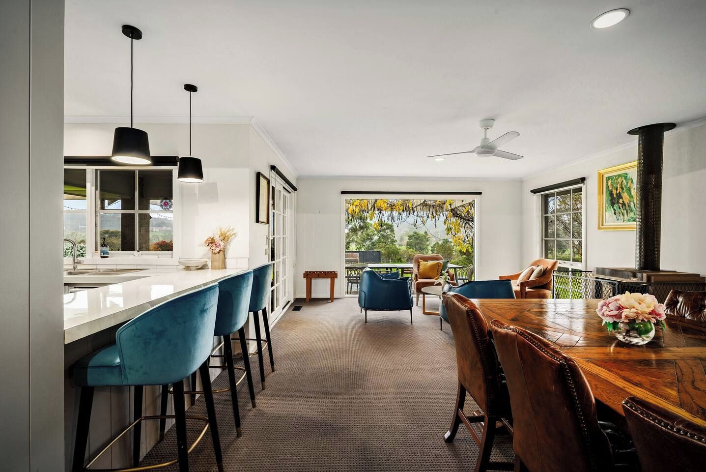 A modern kitchen with a bar area, a dining table with chairs, and a view of the outdoors.
