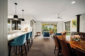 Una cocina moderna con barra, una mesa de comedor con sillas y vistas al exterior.