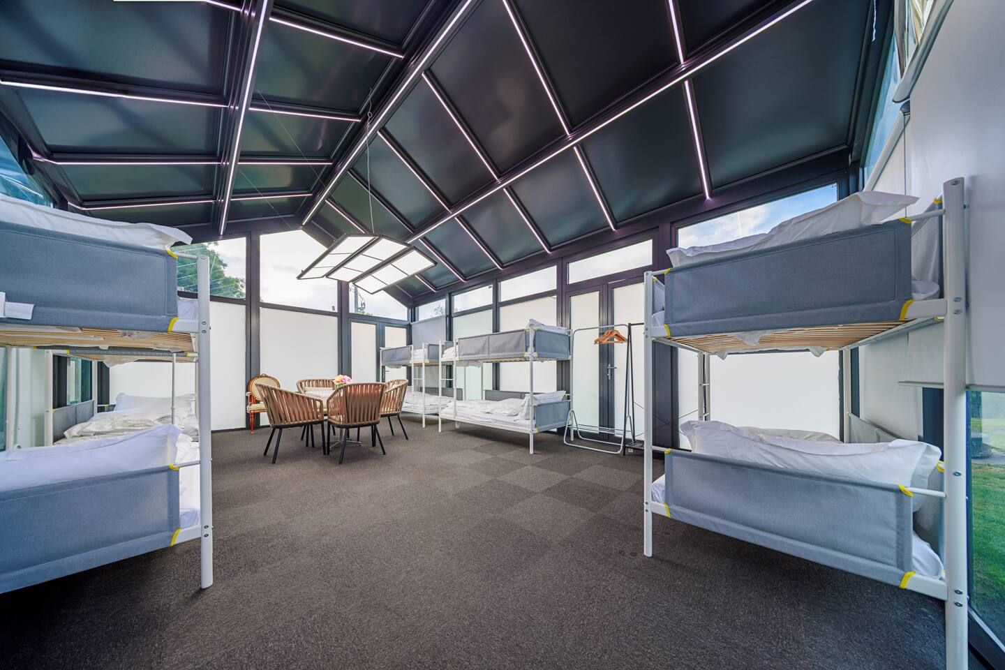 A bunk room with bunk beds, a table, chairs, and a window.