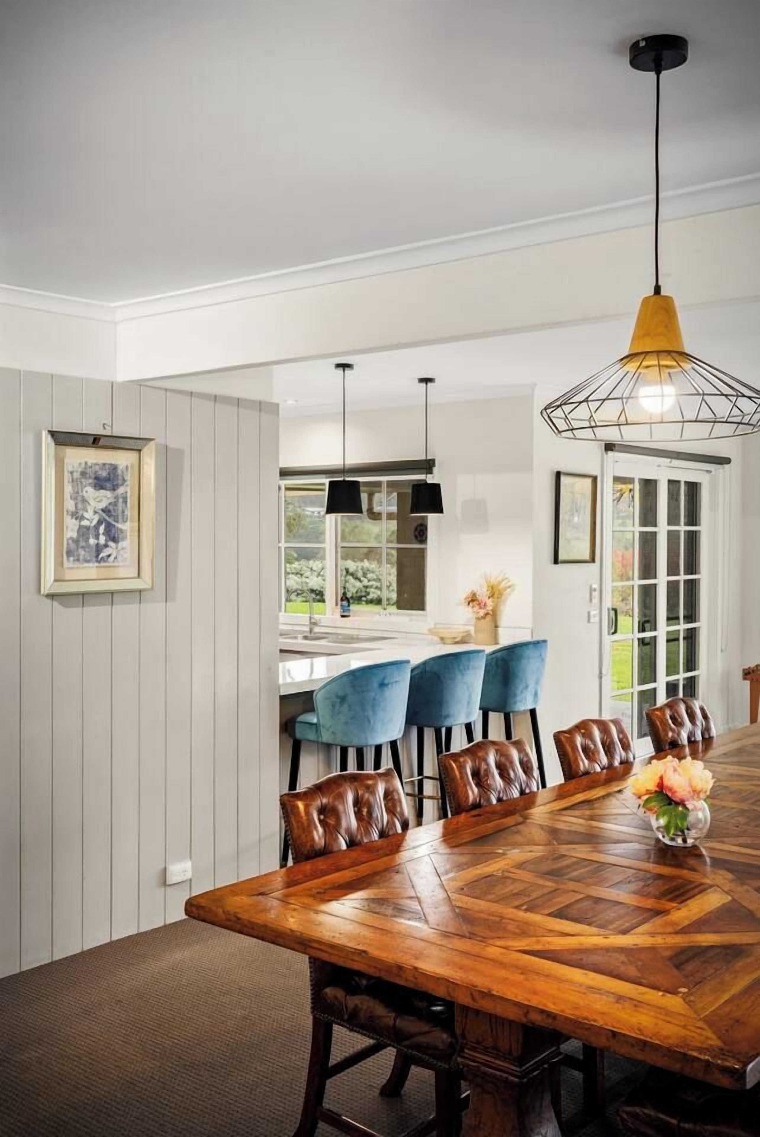 A dining area with a wooden table, blue chairs, and a pendant light.