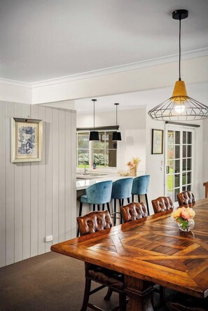 A dining area with a wooden table, blue chairs, and a pendant light. - Yarra Valley Farmhouse | Alpacas Firepit Space Pod (Wonga Park)