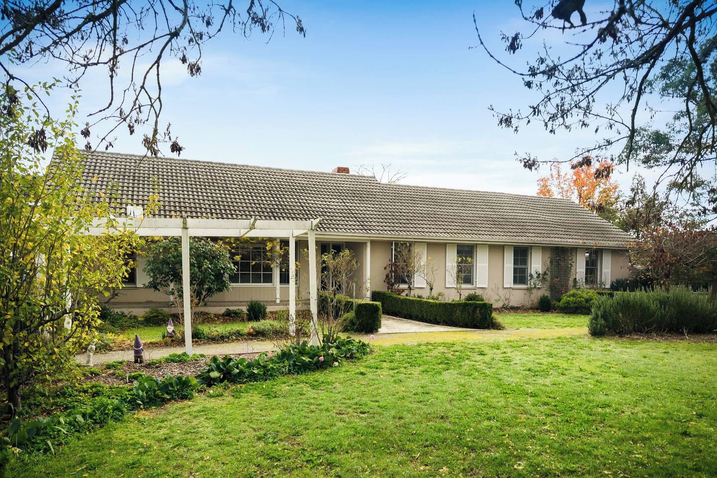 A two-story building with a covered patio area, surrounded by a well-maintained garden with various plants and shrubs.