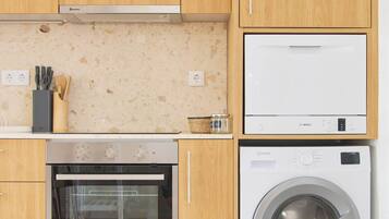 Een moderne keuken met houten kastjes, een inbouwoven, een wasmachine en een magnetron.
