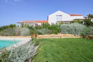 Ein modernes Haus mit Pool, umgeben von gepflegtem Rasen und Sträuchern.