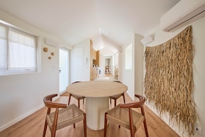 Un espace repas moderne avec une table ronde et quatre chaises, une cuisine en arrière-plan et une décoration murale.