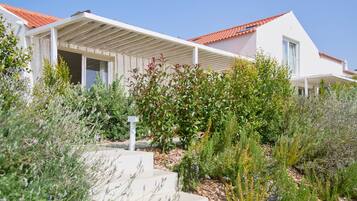 Una casa moderna amb teulada de rajola vermella, parets exteriors blanques i un porxo cobert.