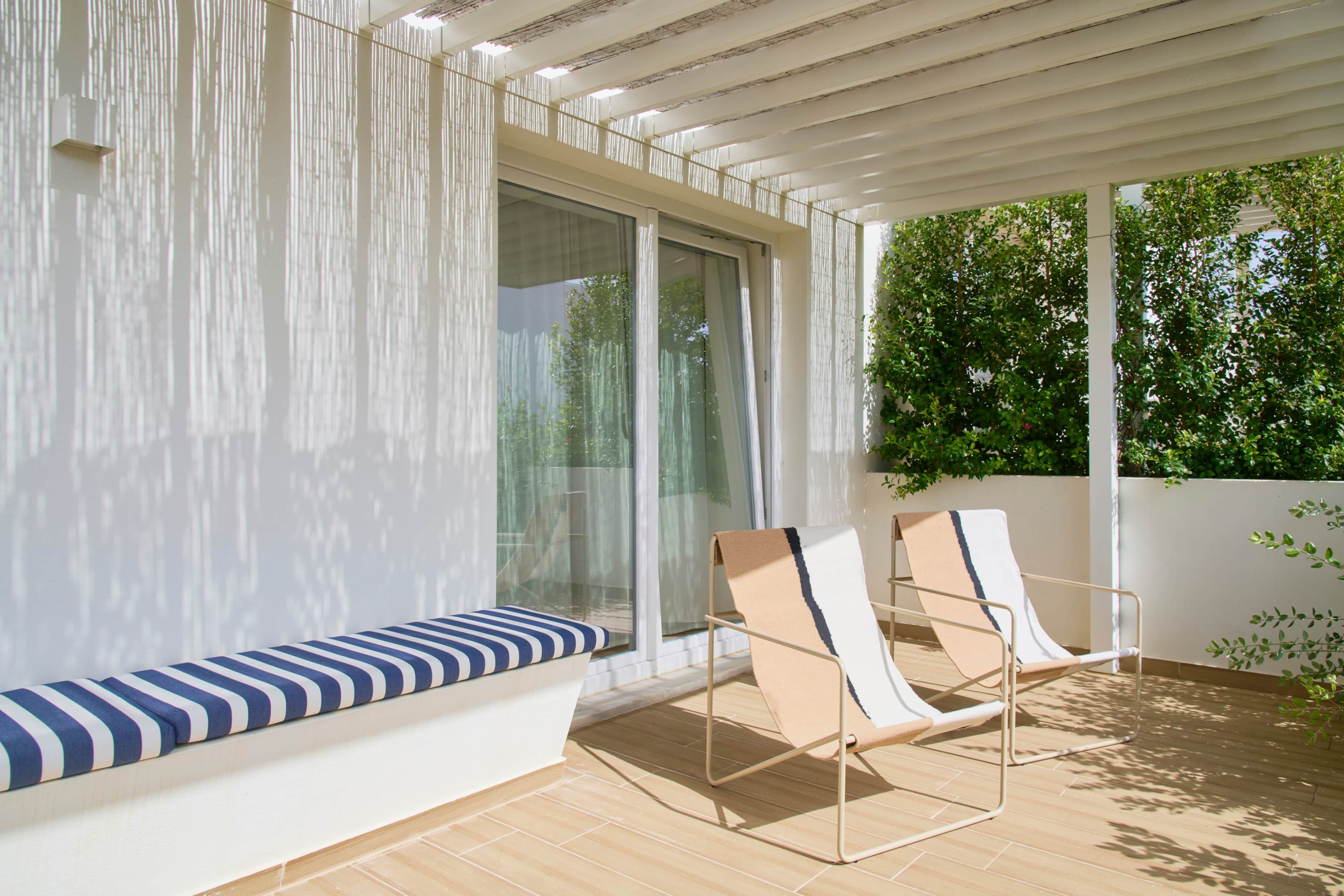 A modern outdoor seating area with a bench and two lounge chairs.