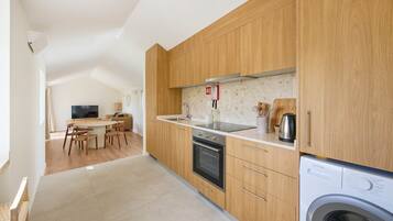 A modern kitchen with wooden cabinets, a built-in oven, and a washing machine.