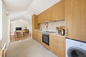 Een moderne keuken met houten kastjes, een inbouwoven en een wasmachine.