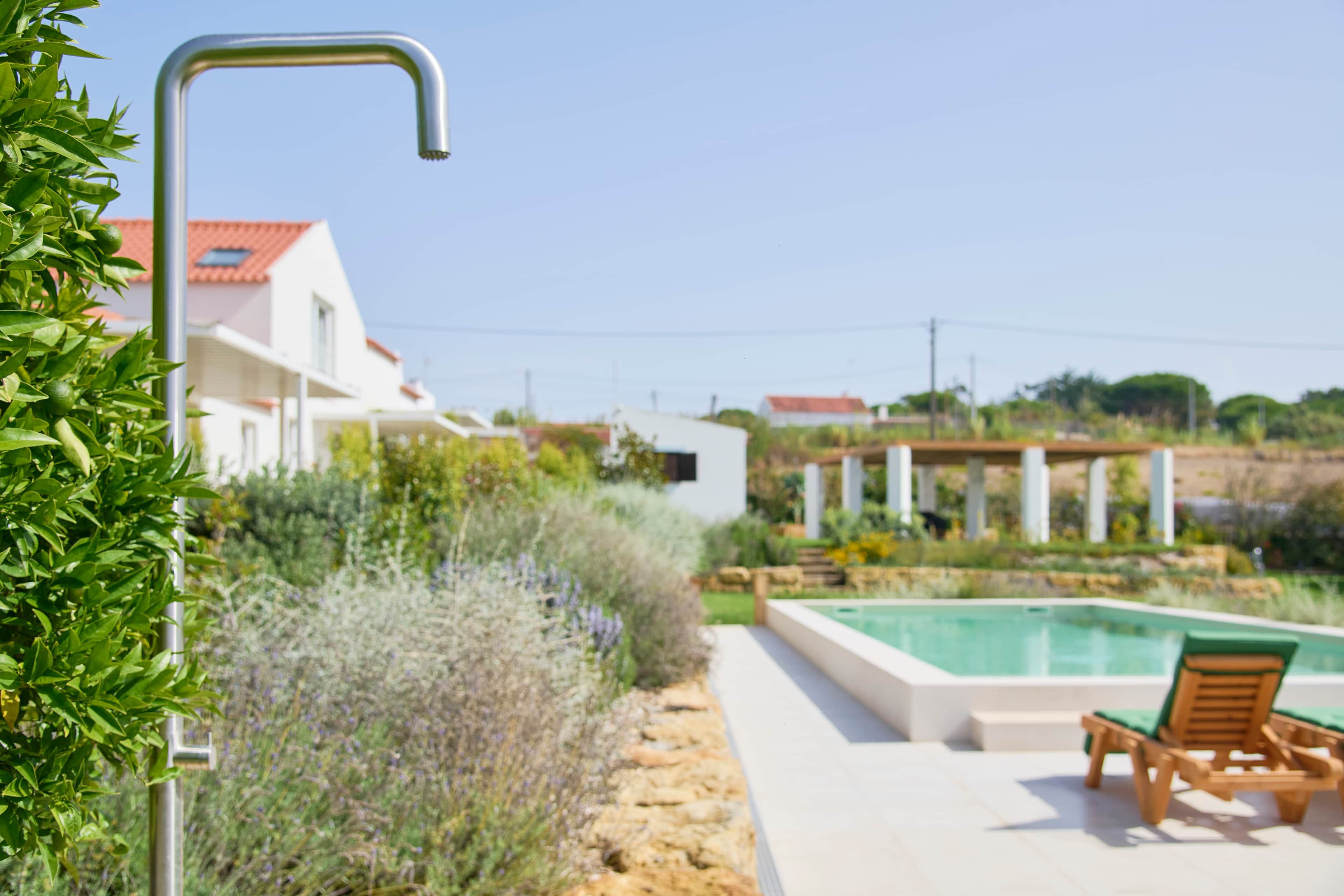 Zona de piscina amb vista clara a una casa, una estructura metàl·lica i una cadira de fusta.