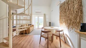 A modern interior with a wooden floor, a round table with chairs, a sofa, and a bookshelf.